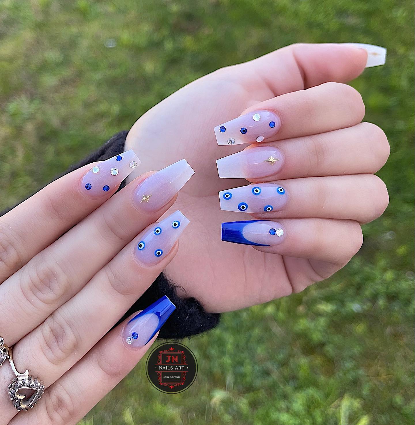 Long coffin shaped clear nails with blue French tips and evil eye nail arts