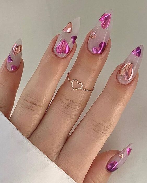 Long stiletto shaped clear nails with chrome pink hearts nail art