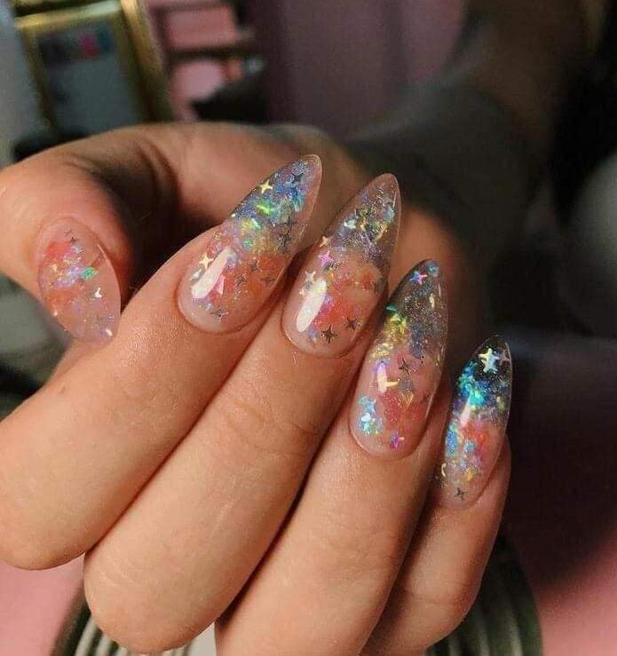 Long almond shaped clear nails with shimmering stars and glitters