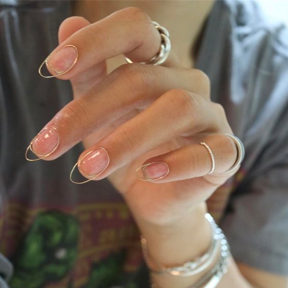 Medium round shaped clear nails with gold outlines and French tips