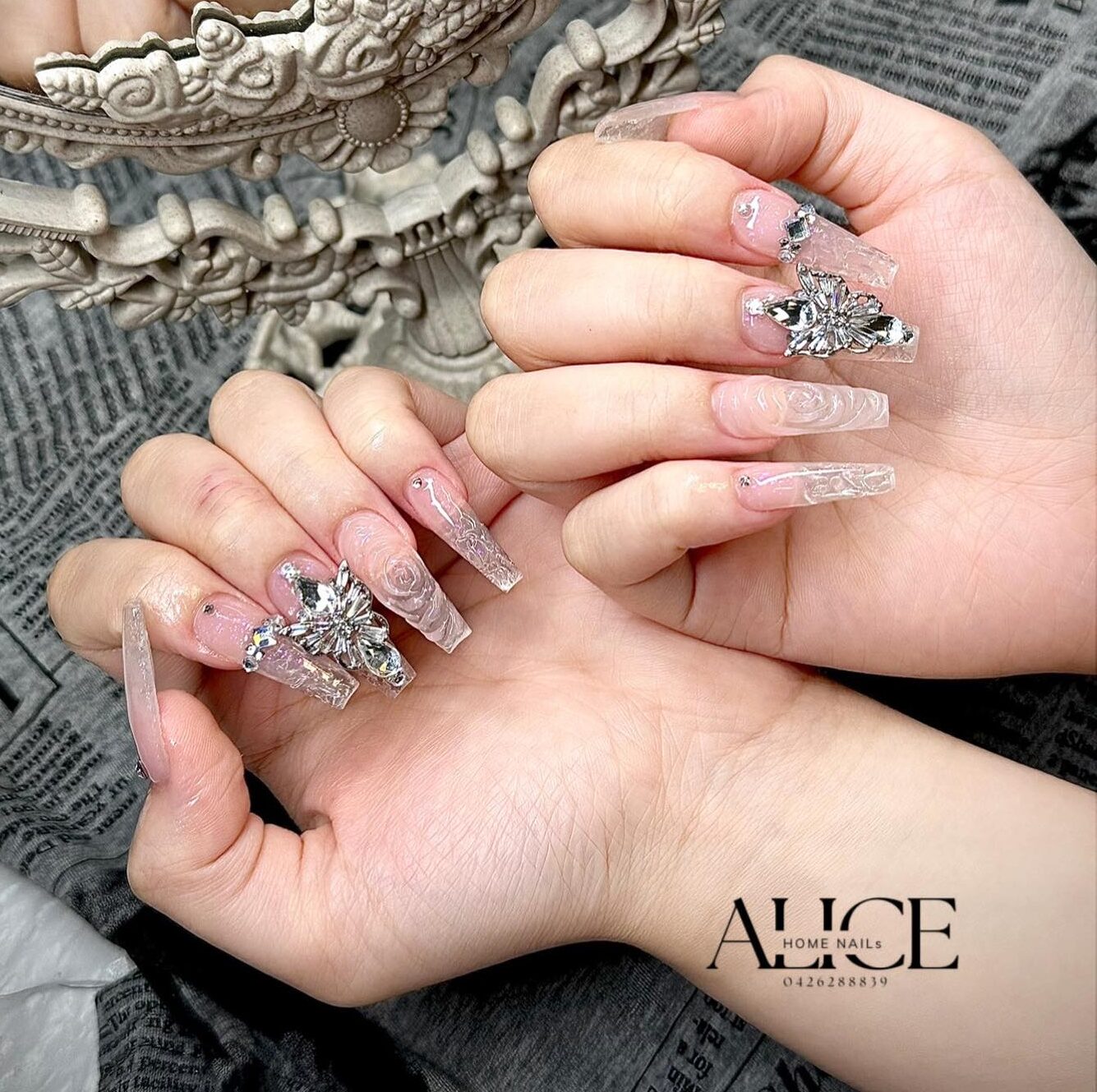 Long coffin shaped clear nails with stylish rhinestones, flower nail art, and 3D bling