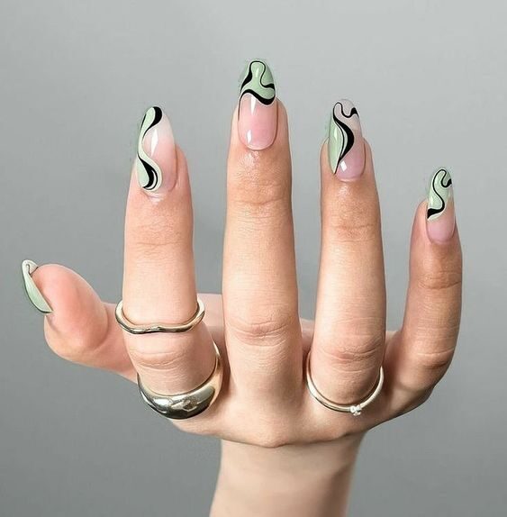 Clear round nails with black and pale green swirling patterns