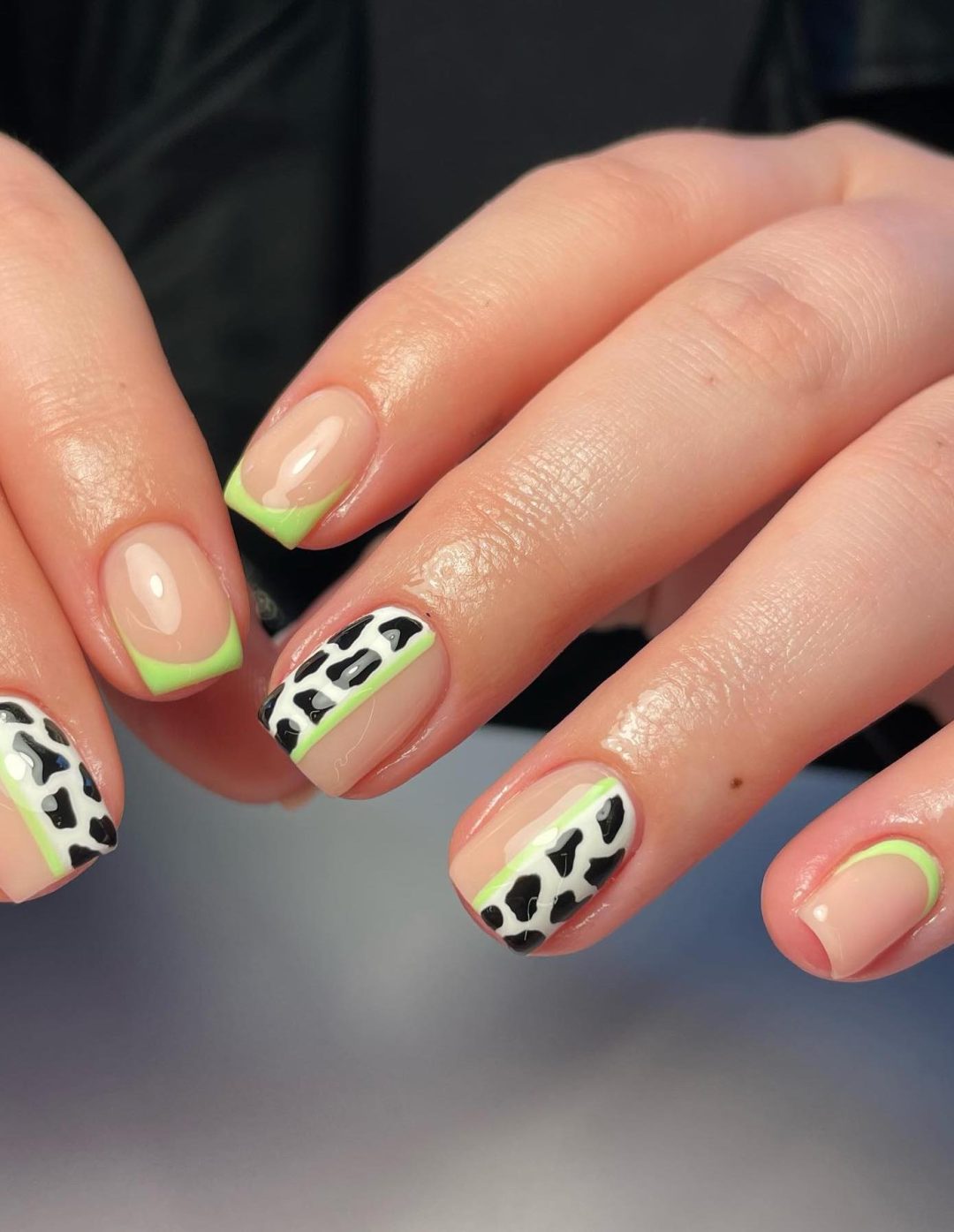 Short neutral nails with neon green and cow print.