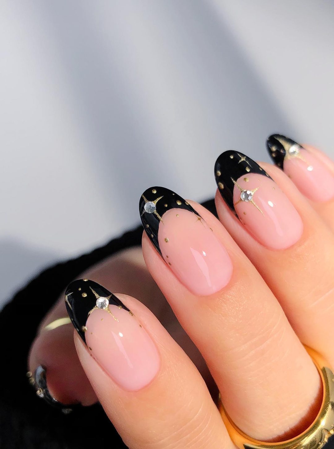 Black French tip nails with gold and silver stars.