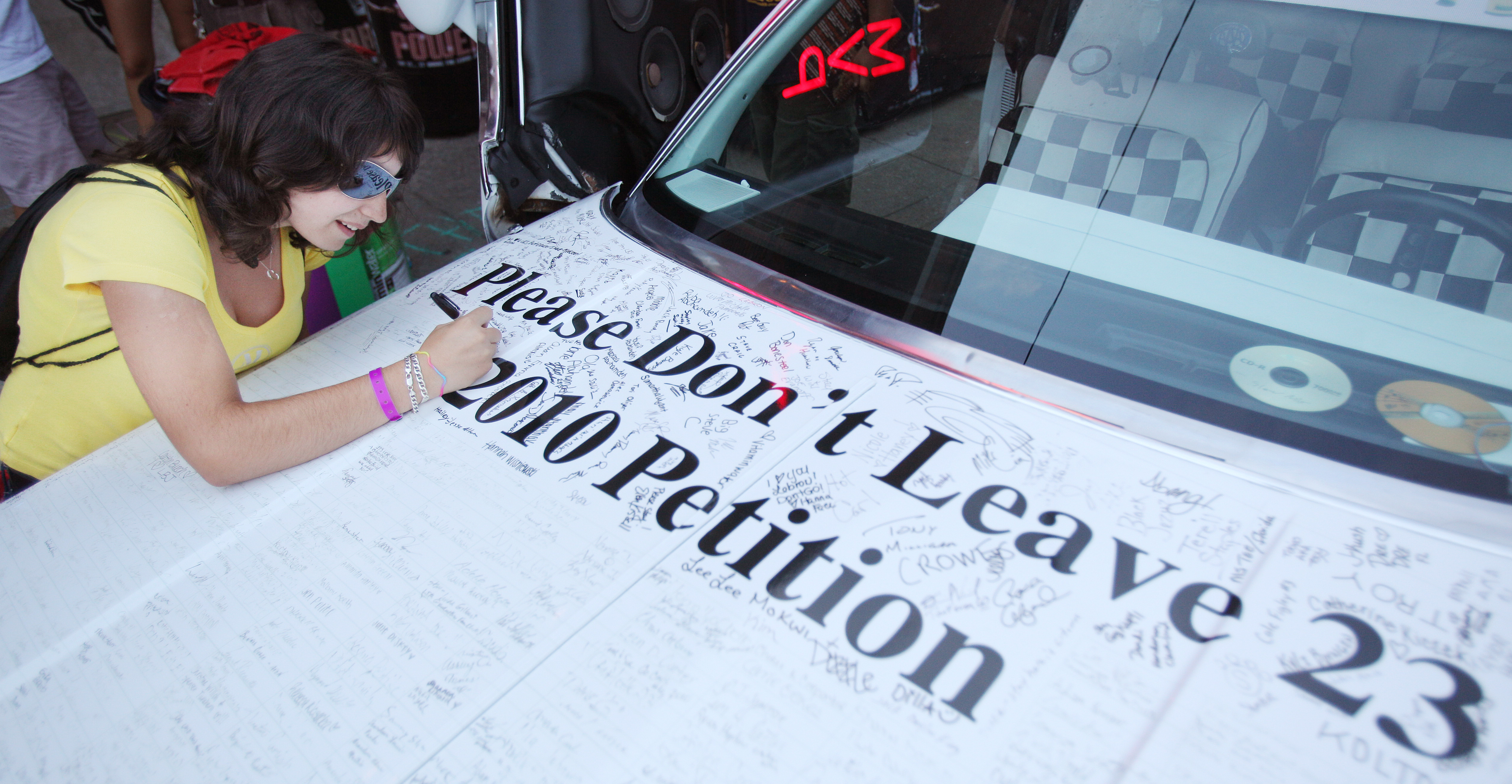 Paloma Fernandez Martin, an exchange student from Spain who has become a big Cleveland Cavaliers and LeBron James fan, signs her name to the car of Kent State student Austin Briggs with Hats Off Entertainment in hopes of keeping James in Cleveland July 8, 2010 outside of harry Buffalos restaurant in Cleveland.   (John Kuntz / The Plain Dealer)